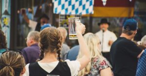 A lively crowd enjoys Oktoberfest outdoors with beer mugs raised. Perfect for festival season visuals.